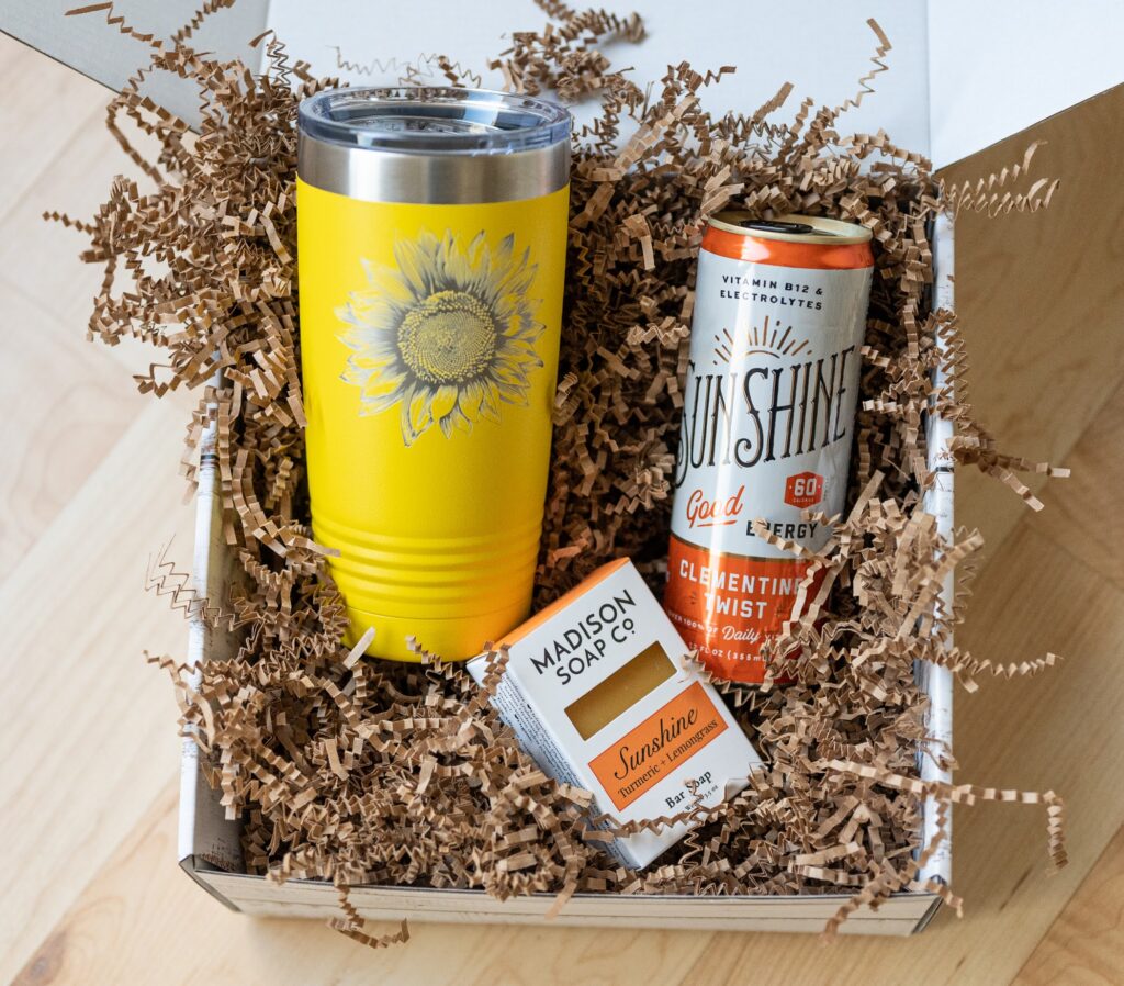 Gift box containing a yellow sunflower tumbler, clementine mist can, and a small soap with brown shredded filler