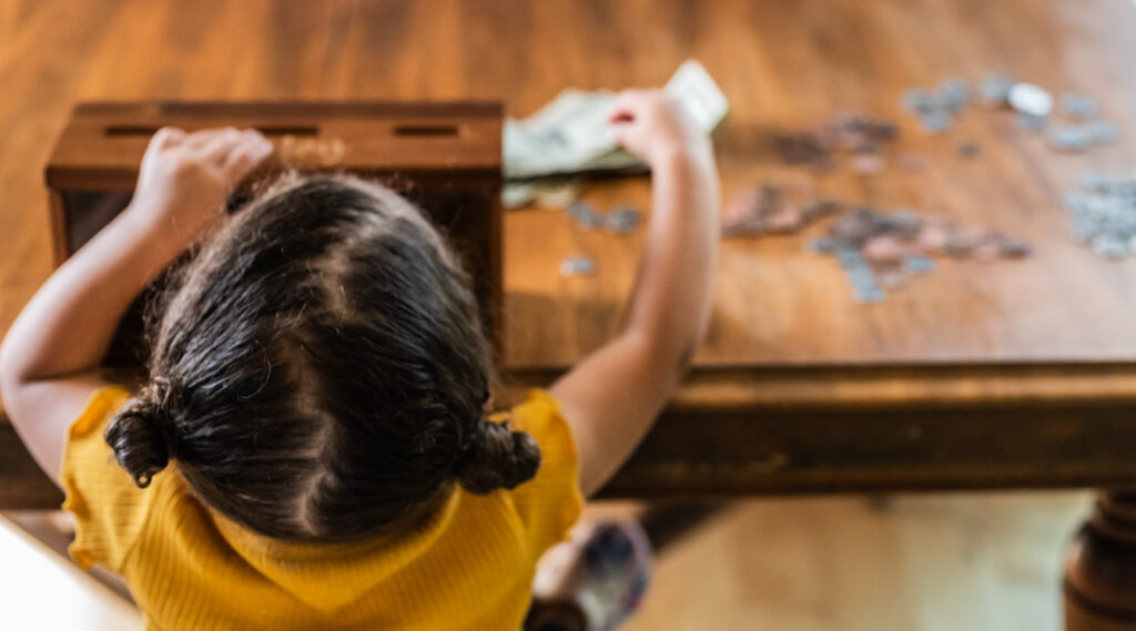 Young girl with hair tied back working on a puzzle at a wooden table, viewed from above, representing clarity and strategy.