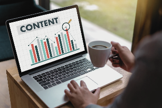 Person holding a coffee cup in front of a laptop displaying a screen with the word content and bar charts, representing content strategy and analytics.
