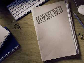 Top secret file folder on a wooden desk with a keyboard, notepads, paper clips, and a pencil, representing business confidentiality and strategy.