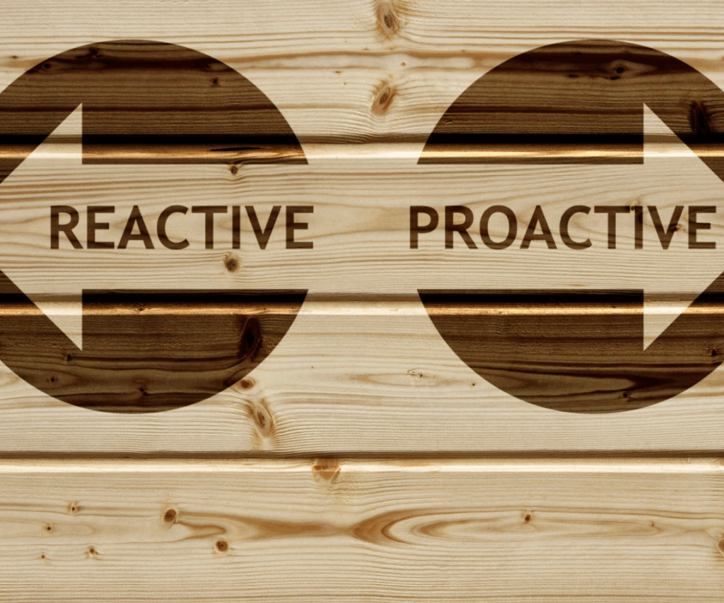 Wooden wall with two large arrows labeled “REACTIVE” pointing left and “PROACTIVE” pointing right, illustrating marketing strategy choices for businesses.